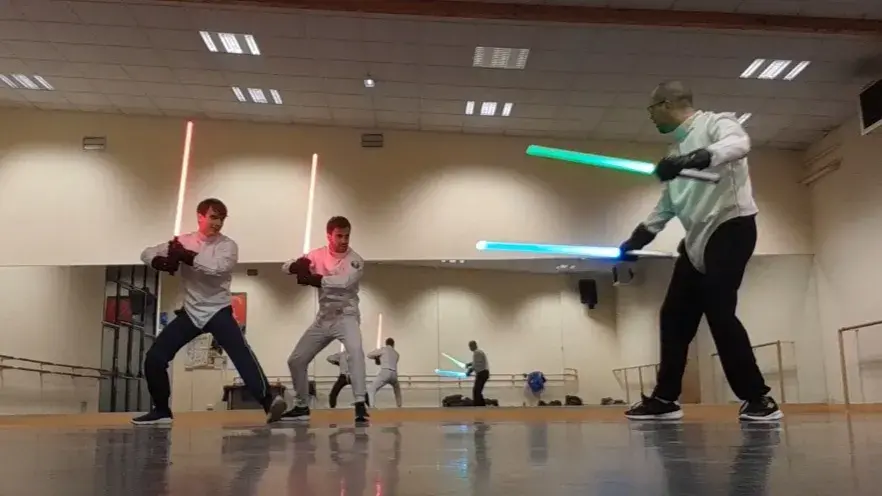 Trois adultes en garde, sabres laser allumés.