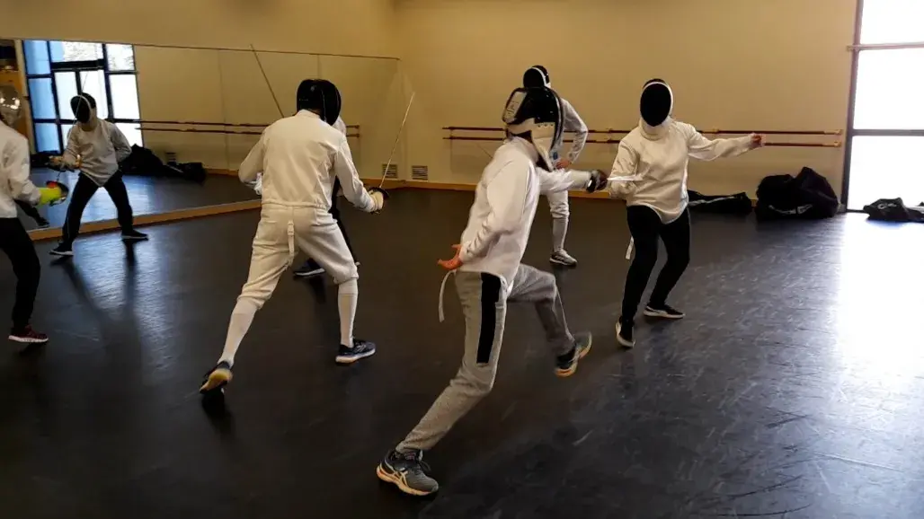 Deux enfants en protections croisent leurs sabres laser.